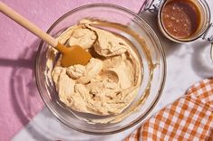 a glass bowl filled with peanut butter next to two spoons