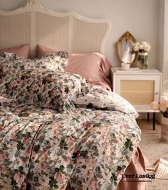 a bed with pink and white flowers on it in front of a mirror next to a dresser