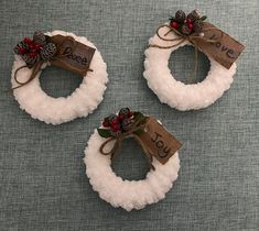 three small wreaths with pine cones and red berries on them