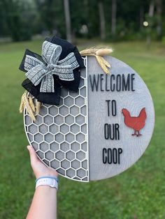 a person holding up a welcome sign with a rooster and hen design on it's side