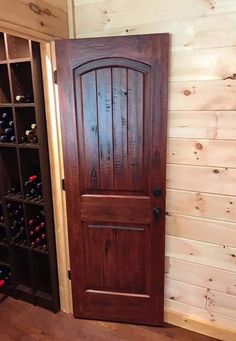 a wooden door is opened to reveal a wine cellar