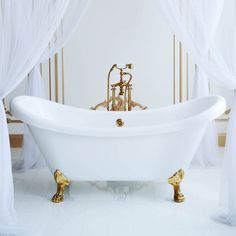 an ornate claw foot bathtub in a white bathroom with gold fixtures and drapes