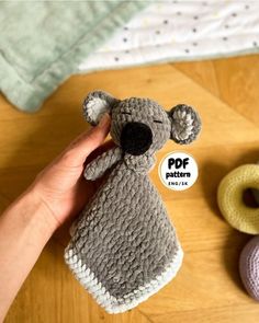 a hand holding a small stuffed animal next to other crocheted toys on a wooden floor