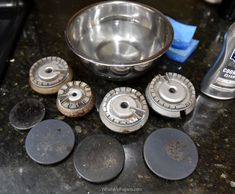 several metal knobs are sitting next to a bowl on a counter top with cleaning supplies nearby