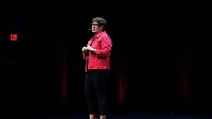 a woman standing on top of a stage with her hands in her pockets and wearing a red shirt