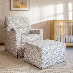 a baby's room with a crib, chair and footstool in it