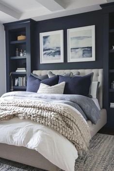 a bedroom with blue walls and white bedding, two pictures on the wall above the bed