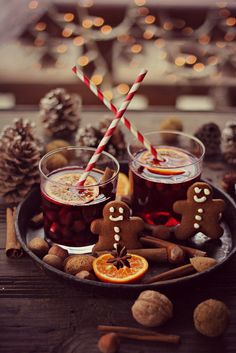 two glasses filled with drinks sitting on top of a plate next to cinnamon sticks and orange slices