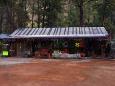 a small store in the middle of a dirt lot with lots of potted plants