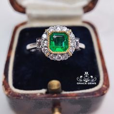 an emerald and diamond ring in a wooden box