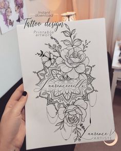 a woman holding up a tattoo design book in her hands, with flowers on the cover