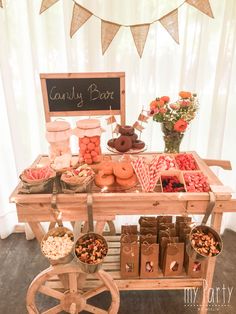 a candy bar is set up on a wooden cart with flowers and candies in it