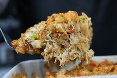 a close up of food in a white dish with a fork sticking out of it