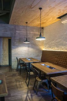 an empty restaurant with wooden tables and brown leather booths, hanging lights and wood flooring