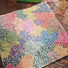 a colorful crocheted rug on a wooden table next to a pair of scissors