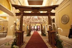 the entrance to an elegant hotel with red carpet and white flowers hanging from the ceiling