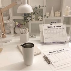 a white desk topped with a coffee cup next to a calendar and other office supplies