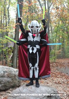 a man dressed as darth vader standing on top of a rock in the woods