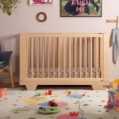 a baby crib with toys on the floor in front of it and pictures above