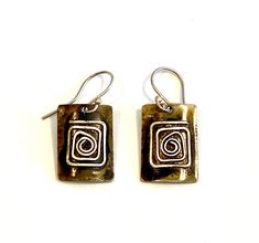 Expertly handcrafted in Oaxaca, Mexico by Zapotec artisan, Felipe, the Mitla earrings feature a 3/4" richly patinaed metal charm with silver "greca" symbols in bas-relief, often seen in ancient Zapotec culture. These handcrafted earrings are fair trade verified and made with silver earring hooks. Total length is 1.25". Coordinate with the Greca Necklace for a great new look! Hood River, Bas Relief, Handcrafted Earrings, Earring Hooks, Metal Charm, Silver Earring, Fair Trade, Halloween Shopping, Jewelry Earrings Dangle