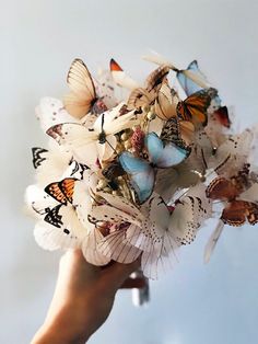 a person holding a bouquet of butterflies in their hand