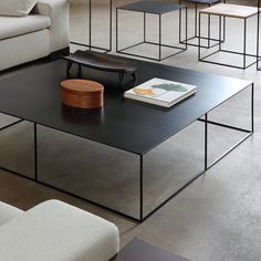 a living room filled with furniture and a book on top of a black coffee table