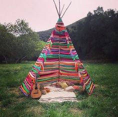 a colorful teepee tent sitting on top of a lush green field