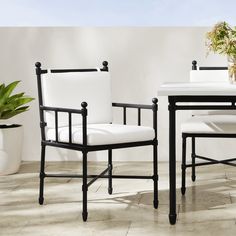 two white chairs and a table with potted plants