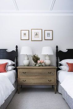 two beds in a room with white walls and pictures on the wall above them,