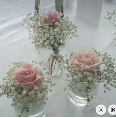 three vases filled with pink roses and baby's breath flowers on a table