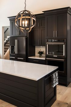 a modern kitchen with black cabinets and white counter tops, an island in the middle