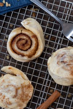 three cinnamon rolls sitting on top of a cooling rack next to a fork and spoon