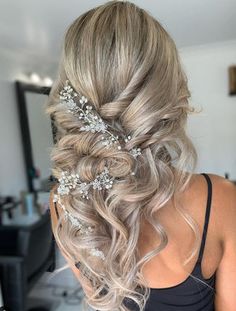 a woman with long blonde hair wearing a wedding hairstyle and flowers in her hair