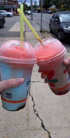 two people holding up drinks on the sidewalk