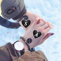 two people holding hands with black hearts on them and one has a watch in the other hand