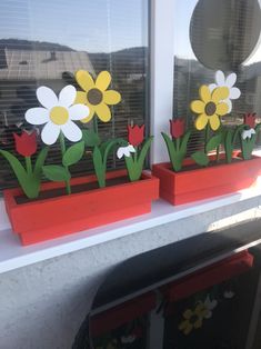 two flower pots with flowers in them sitting on a window sill