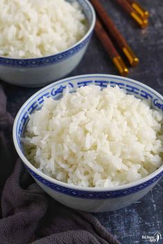 two bowls filled with white rice next to chopsticks