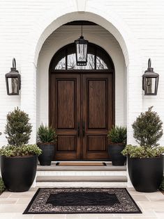 two large planters are on the front steps of a house with an entry door