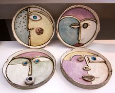 four ceramic plates with faces painted on them