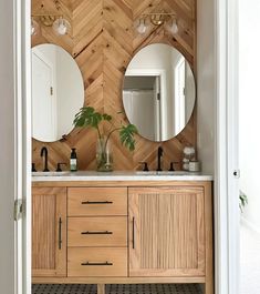 a bathroom with two round mirrors on the wall and wood paneling around the sink