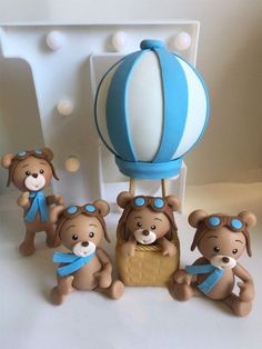 a group of brown teddy bears standing next to a blue and white hot air balloon