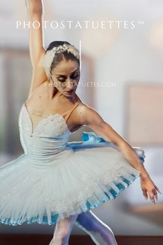 a young ballerina in white tutu with her arms up and legs spread out