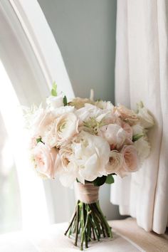 a bouquet of flowers sitting on top of a window sill next to a curtain