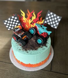 a birthday cake decorated with monster trucks and flags