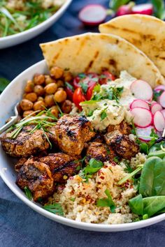 a bowl filled with meat, rice and veggies next to pita bread