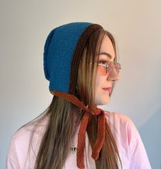 a woman with long hair wearing a knitted hat and scarf on her head, looking off to the side