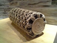 a roll of jute sitting on top of a wooden table next to a wall