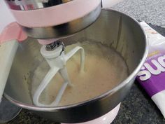 a pink mixer is sitting on the counter next to a bag of doughnuts