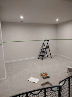 an empty room with a ladder and some books on the floor in front of it