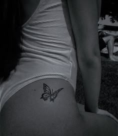 a black and white photo of a woman's stomach with a butterfly tattoo on it